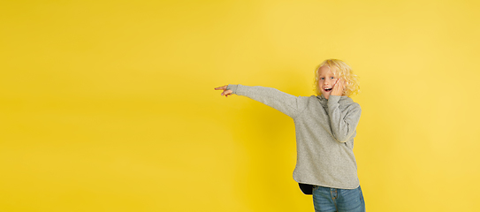 Image showing Portrait of little caucasian boy with bright emotions isolated on yellow studio background