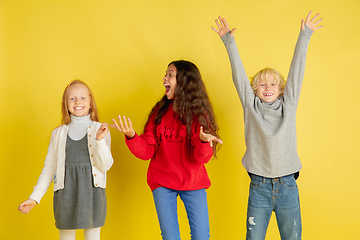 Image showing Portrait of little caucasian children with bright emotions isolated on yellow studio background