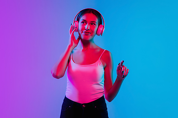 Image showing Young caucasian woman\'s portrait on gradient blue-purple studio background in neon light