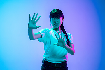 Image showing Young asian woman\'s portrait on gradient blue-purple studio background in neon light