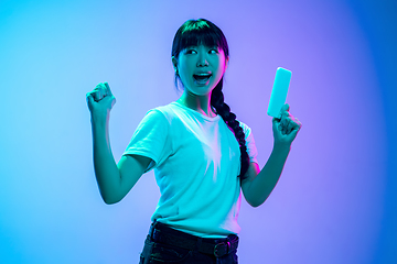 Image showing Young asian woman\'s portrait on gradient blue-purple studio background in neon light