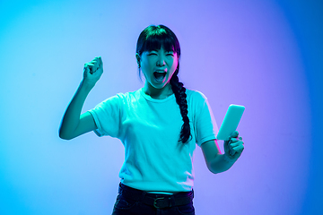 Image showing Young asian woman\'s portrait on gradient blue-purple studio background in neon light