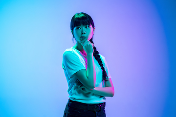 Image showing Young asian woman\'s portrait on gradient blue-purple studio background in neon light