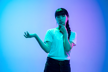 Image showing Young asian woman\'s portrait on gradient blue-purple studio background in neon light