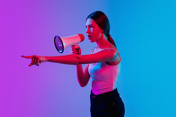 Image showing Young caucasian woman\'s portrait on gradient blue-purple studio background in neon light