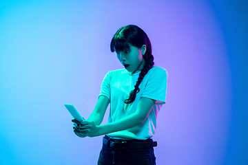 Image showing Young asian woman\'s portrait on gradient blue-purple studio background in neon light