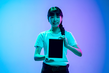 Image showing Young asian woman\'s portrait on gradient blue-purple studio background in neon light