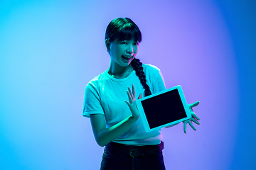 Image showing Young asian woman\'s portrait on gradient blue-purple studio background in neon light