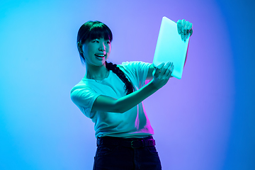 Image showing Young asian woman\'s portrait on gradient blue-purple studio background in neon light