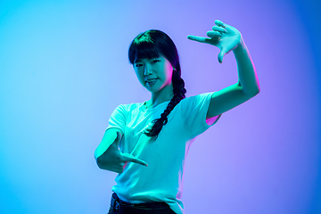 Image showing Young asian woman\'s portrait on gradient blue-purple studio background in neon light