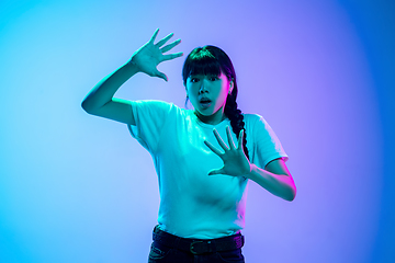 Image showing Young asian woman\'s portrait on gradient blue-purple studio background in neon light