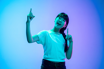 Image showing Young asian woman\'s portrait on gradient blue-purple studio background in neon light