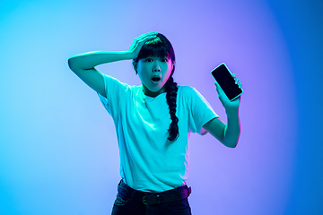 Image showing Young asian woman\'s portrait on gradient blue-purple studio background in neon light