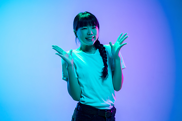 Image showing Young asian woman\'s portrait on gradient blue-purple studio background in neon light