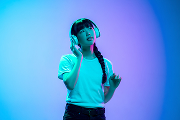 Image showing Young asian woman\'s portrait on gradient blue-purple studio background in neon light