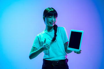 Image showing Young asian woman\'s portrait on gradient blue-purple studio background in neon light