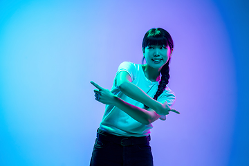 Image showing Young asian woman\'s portrait on gradient blue-purple studio background in neon light