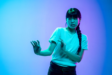 Image showing Young asian woman\'s portrait on gradient blue-purple studio background in neon light