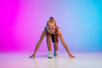 Image showing Teenage girl running, jogging against gradient pink-blue neon studio background in motion