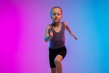 Image showing Teenage girl running, jogging against gradient pink-blue neon studio background in motion