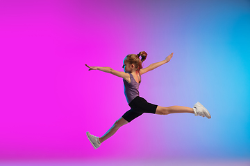 Image showing Teenage girl running, jogging against gradient pink-blue neon studio background in motion