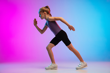 Image showing Teenage girl running, jogging against gradient pink-blue neon studio background in motion