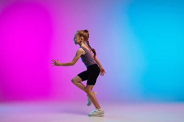 Image showing Teenage girl running, jogging against gradient pink-blue neon studio background in motion