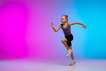 Image showing Teenage girl running, jogging against gradient pink-blue neon studio background in motion