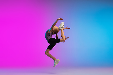 Image showing Teenage girl running, jogging against gradient pink-blue neon studio background in motion