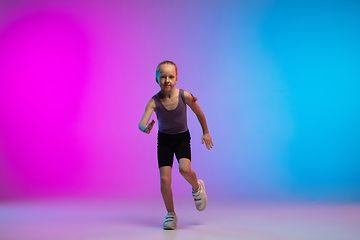 Image showing Teenage girl running, jogging against gradient pink-blue neon studio background in motion