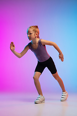 Image showing Teenage girl running, jogging against gradient pink-blue neon studio background in motion