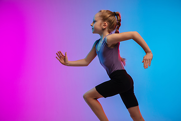 Image showing Teenage girl running, jogging against gradient pink-blue neon studio background in motion