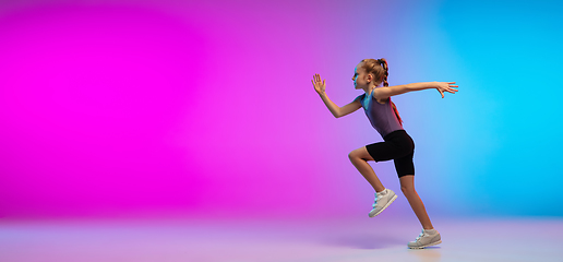 Image showing Teenage girl running, jogging against gradient pink-blue neon studio background in motion