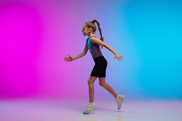 Image showing Teenage girl running, jogging against gradient pink-blue neon studio background in motion