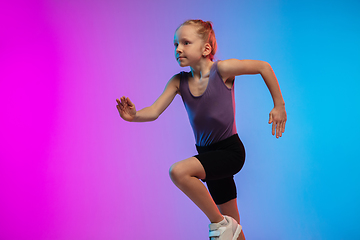 Image showing Teenage girl running, jogging against gradient pink-blue neon studio background in motion