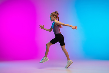 Image showing Teenage girl running, jogging against gradient pink-blue neon studio background in motion