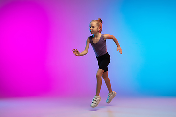 Image showing Teenage girl running, jogging against gradient pink-blue neon studio background in motion