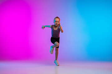 Image showing Teenage girl running, jogging against gradient pink-blue neon studio background in motion