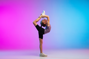 Image showing Teenage girl running, jogging against gradient pink-blue neon studio background in motion