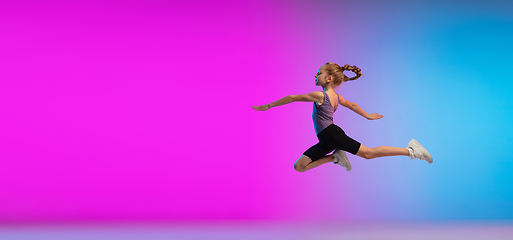 Image showing Teenage girl running, jogging against gradient pink-blue neon studio background in motion