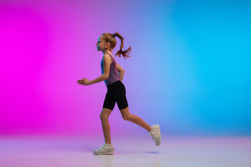 Image showing Teenage girl running, jogging against gradient pink-blue neon studio background in motion