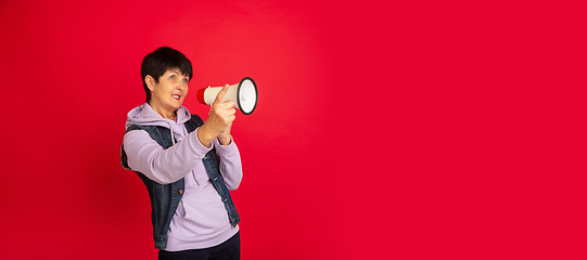 Image showing Senior woman isolated on red background. Tech and joyful elderly lifestyle concept