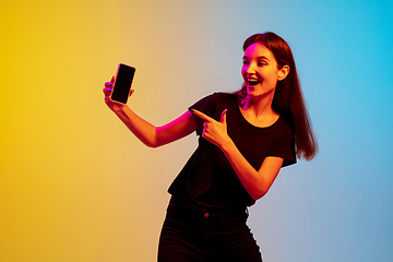 Image showing Young caucasian woman\'s portrait on gradient blue-yellow studio background in neon light