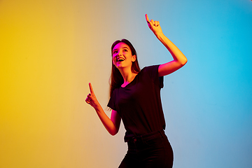 Image showing Young caucasian woman\'s portrait on gradient blue-yellow studio background in neon light