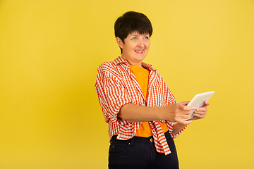 Image showing Senior woman isolated on yellow background. Tech and joyful elderly lifestyle concept