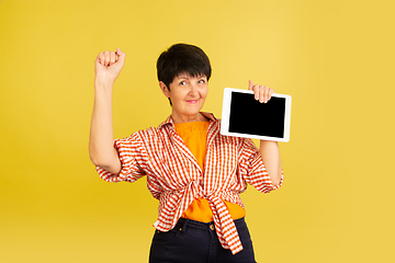 Image showing Senior woman isolated on yellow background. Tech and joyful elderly lifestyle concept