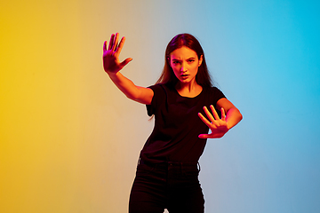 Image showing Young caucasian woman\'s portrait on gradient blue-yellow studio background in neon light