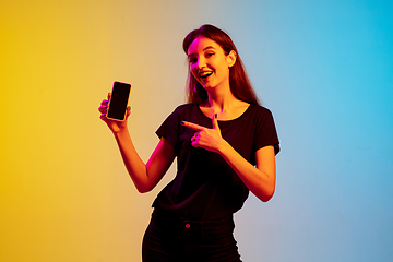 Image showing Young caucasian woman\'s portrait on gradient blue-yellow studio background in neon light