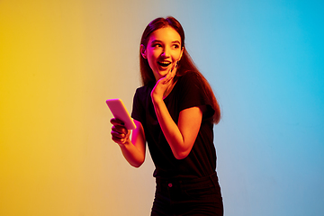 Image showing Young caucasian woman\'s portrait on gradient blue-yellow studio background in neon light