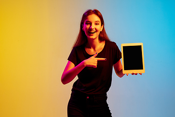 Image showing Young caucasian woman\'s portrait on gradient blue-yellow studio background in neon light